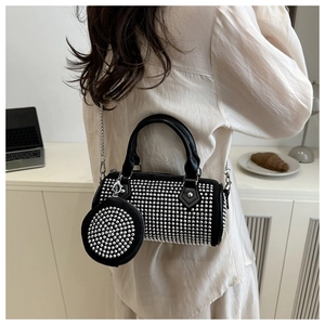 Macro detail of black cylindrical crossbody bag with silver rhinestones and chain strap