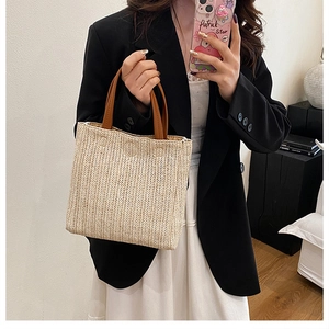 Close-up of straw woven tote bag with V-shaped texture and brown leather handles