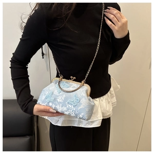 Detail of light blue floral embroidery and butterfly ornaments on a vintage style handbag