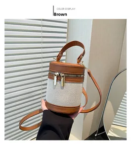 Detail of a brown leather and canvas cylinder bucket bag with golden double zippers