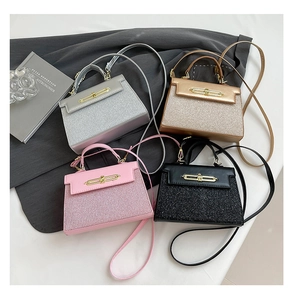 Glittery Kelly style handbags in silver, gold, pink, and black on a textured blazer