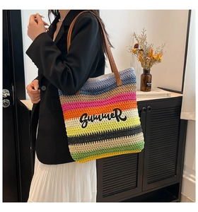 Detail view of colorful striped straw tote bag with Summer embroidery and leather handles