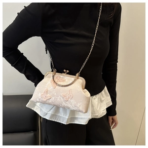 Detail of elegant beige silk clutch with pink butterfly embroidery and gold kiss lock