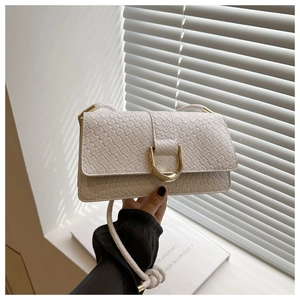 Détail de la texture tissée du sac blanc avec une boucle dorée en forme de D emblématique