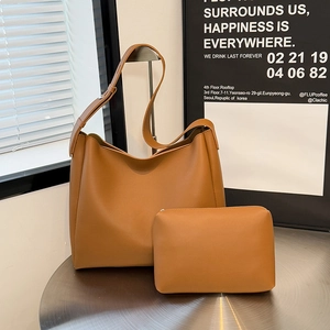 Brown faux leather large tote bag set with matching pouch on a silver metal table