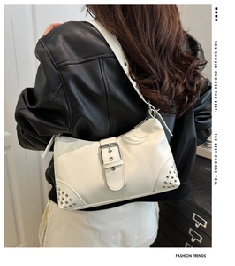 Close-up of cream white retro crescent shoulder bag with metallic rivets and buckle