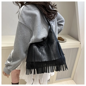 Detail of black crossbody bag featuring long double-layer fringes and premium leather texture