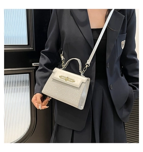 Close-up of silver sequin square bag with golden lock and mirror finish details
