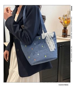 Detail of light blue denim tote with tulip embroidery and white lace bow decoration