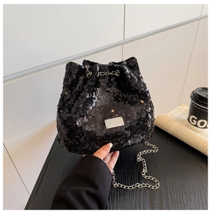 Detail of a black sequined bucket bag featuring silver chain strap and drawstring closure