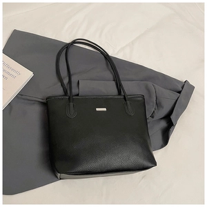 Gros plan du sac cabas en cuir litchi noir avec plaque logo métallique rectangulaire
