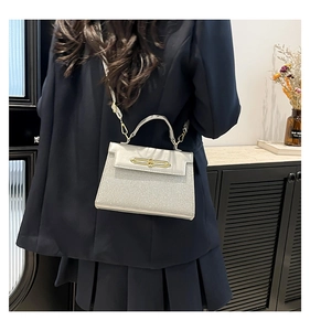 Detail of glitter texture messenger bag with elegant golden hardware and top handle