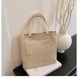 Detail of beige straw tote bag with V-shaped woven texture and smooth top handles