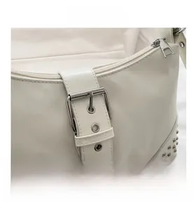 Detail showing silver buckle and rivet studs on a white leather baguette shoulder bag