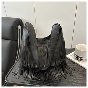 Détail d'un sac bandoulière noir en similicuir avec de longues franges de style bohème