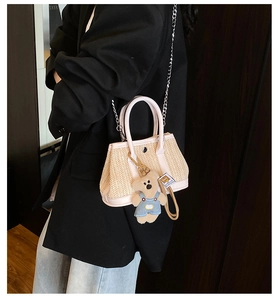 Detail of straw woven crossbody bag with pink leather trim and a cute teddy bear charm