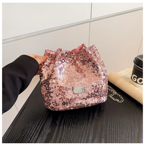 Detailed view of pink sequin bucket bag with silver chain strap on a black desk