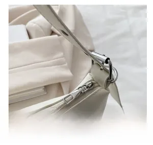 Detailed close-up of smooth silver metal zipper and hardware on white leather tote bag