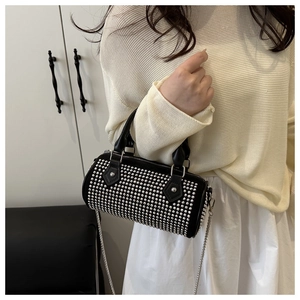 Detail of black cylindrical bag with silver studs and a metallic chain strap on model