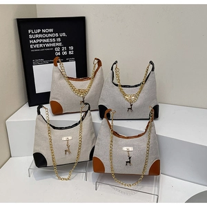 Detail of canvas shoulder bags with leather trim, gold chain, and deer pendant charm
