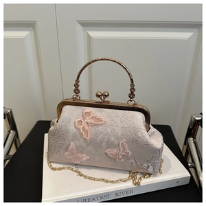 Détails de la broderie papillon et du fermoir métallique sur un sac en satin rose