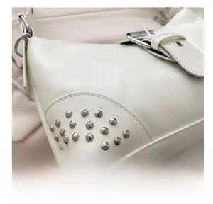 Detailed shot of white PU leather shoulder bag with silver rivet studs and metal buckle