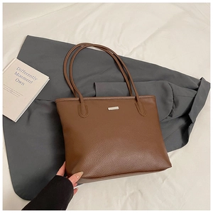 Detail of dark brown pebble leather tote bag with silver metal trim and long handles