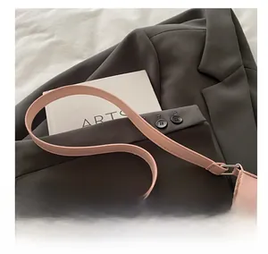 Detailansicht der rosa PU-Ledertasche mit silbernen Ösen auf einem braunen Blazer