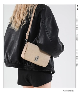 Detail of champagne gold crossbody bag with metallic logo and adjustable strap