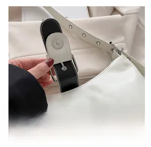Close-up of a silver magnetic metal clasp on a white leather rivet tote bag