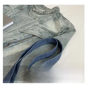 Detail shot of blue denim tote bag with reinforced woven handle and floral embroidery