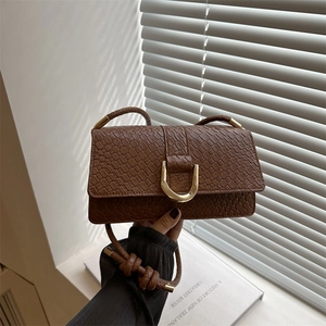 Sac baguette marron à texture tressée avec boucle fer à cheval dorée et bandoulière tissée