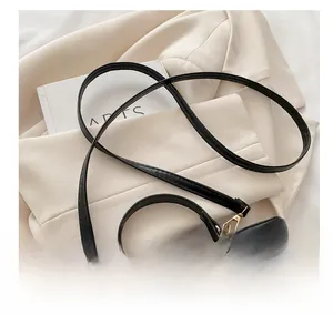 Detail of adjustable leather strap and golden zipper on black box-style chain bag
