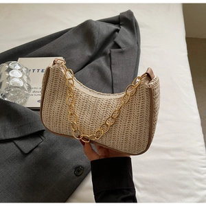 Close-up of crescent straw bag with chunky gold chain strap and woven texture