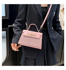 Close-up of pink sequin leather handbag with gold twist lock and crossbody strap