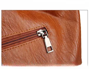 Detailed view of silver-plated zipper and litchi texture on brown leather handbag