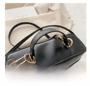 Detailed close-up of smooth black leather handle with elegant pale gold D-ring hardware