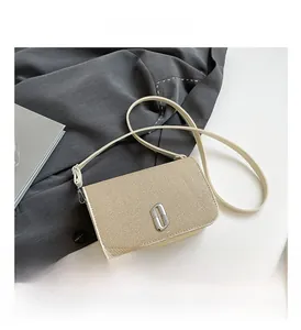 Detail of cream crossbody bag featuring woven texture and rhinestone rectangular buckle