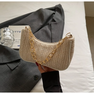 Detailed view of beige crescent straw bag with white leather trim and gold chain strap