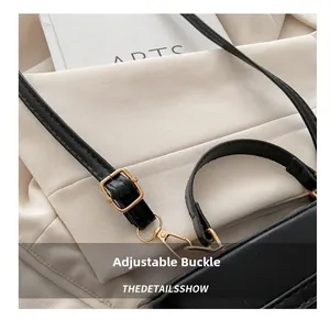 Detail shot of black leather handbag with adjustable gold metal buckle and lobster clasp