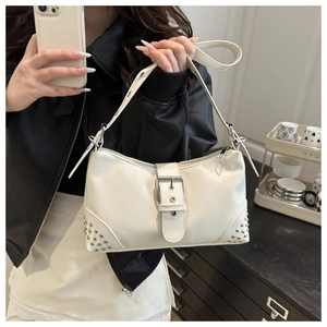 Detail of creamy white glossy shoulder bag with silver buckles and stud decorations