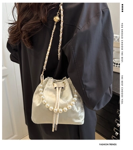 Detailed view of floral embroidery on a satin bucket bag with elegant pearl handle
