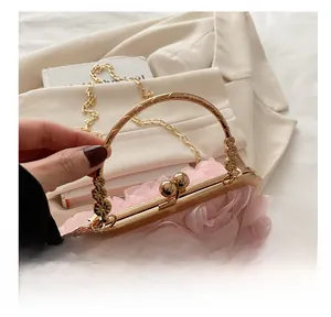Detailansicht einer rosa Abendtasche mit Blumen, goldenem Griff und Kettengurt