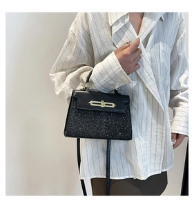 Detail view of the black glitter textured small handbag with gold metal lock closure