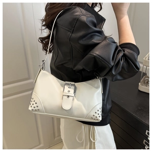 Detail of white faux leather shoulder bag featuring silver rivets and central buckle