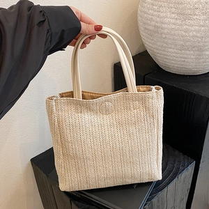 Handwoven straw tote bag with cream leather handles and spacious interior for summer