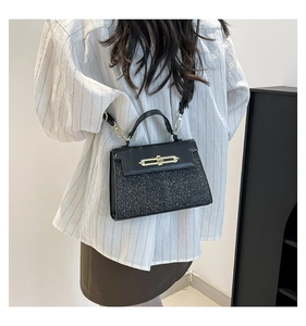 Detailed back view of a black glittery crossbody bag with gold lock on a model