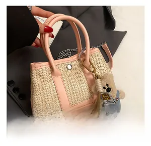 Close-up of beige woven beach bag with pink leather handles and a cute bear charm accessory