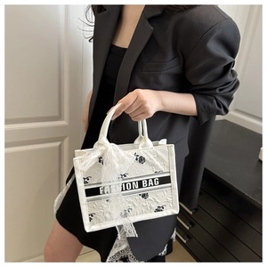 Detailed embroidery of black roses and lace bow on a stylish white tote bag