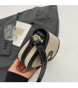 Close-up of contrast stitch canvas shoulder bag with gold hardware and leather trim